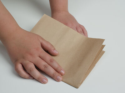 Hand faltet die Papiert&uuml;te quer.
