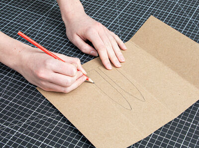 Bleistift zeichnet Hasenohr auf aufgetrennten Milchkarton.