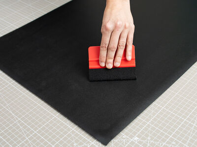 Die Tafelfolie wird mit einer Rakel festgestrichen.