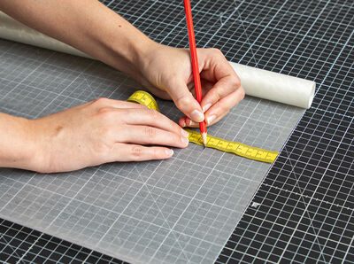 Stift zeichnet Maße auf Rückseitenpapier der Glasfolie.