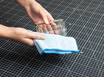 Hand mit Tuch säubert Schraubglas.