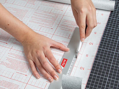 The cutter cuts the “Glitter silver” foil along the ruler.