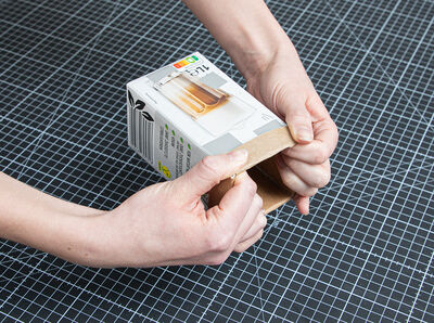 H&auml;nde greifen Milchkarton und schlagen oberen Rand einige Zentimeter breit nach au&szlig;en um.