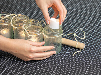 Hand stellt Teelicht in Glas.