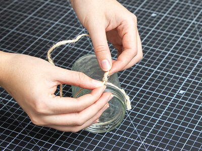 Hände verknoten Schnur zum Aufhängen an Rundschnur.