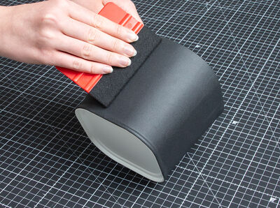 Rakel streicht Tafelfolie auf &Uuml;bertopf fest.