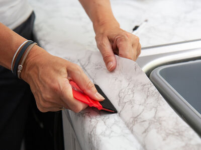 Rakel streicht die Klebefolie fest.