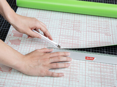 Cutter schneidet entlang eines Lineals die Klebefolie.