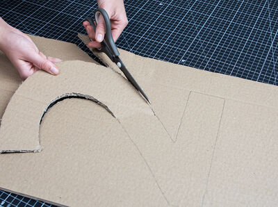 Schere schneidet die Ziffer aus Karton aus.