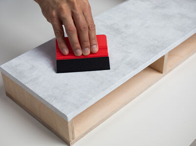 Die Folie auf der Deckplatte des Organizers mit der Rakel gut feststreichen.