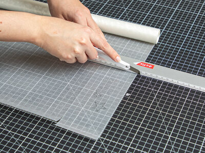 Cutter schneidet Glasfolie entlang des Lineals.