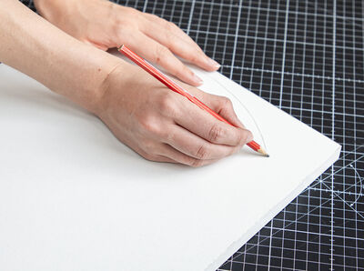 Bleistift zeichnet runde Form auf Holzbrett.