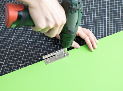 Scharniere werden am Holzbrett geschraubt.