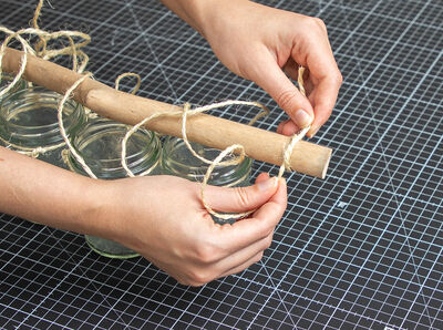 Hände befestigen Schnur am Treibholz.