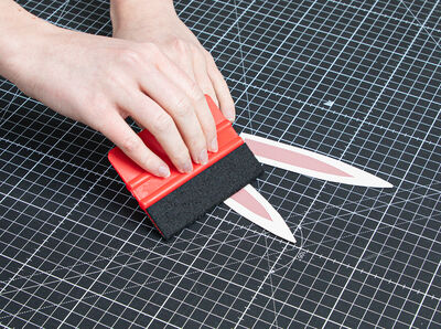 Hand rakelt rosafarbenes Folienst&uuml;ck mittig auf das bereits sandfarben beklebte Ohren-Shape. 