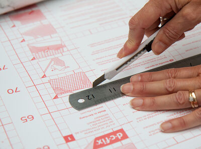 Schere schneidet die Klebefolie zu.