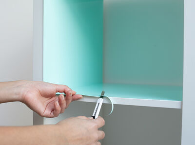 Klebefolie wird an der Kante mit einem Cutter zugeschnitten.