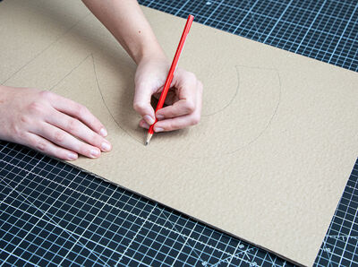 Hand h&auml;lt Stift und zeichnet Umriss der Zahl auf Karton.