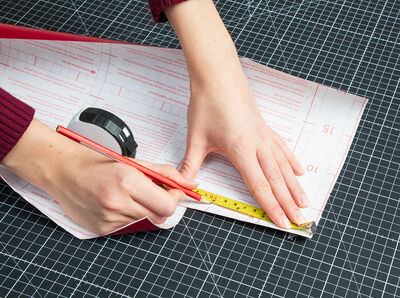 Bleistift zeichnet Maße mit Lineal auf Rückseite der Klebefolie.