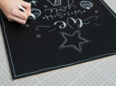 Tafelfolie wird mit einem Stück Kreide beschrieben.