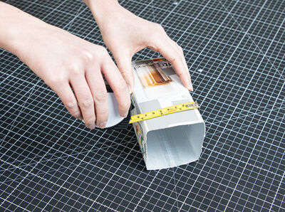 Ma&szlig;band wird an den zugeschnittenen Milchkarton angelegt. 